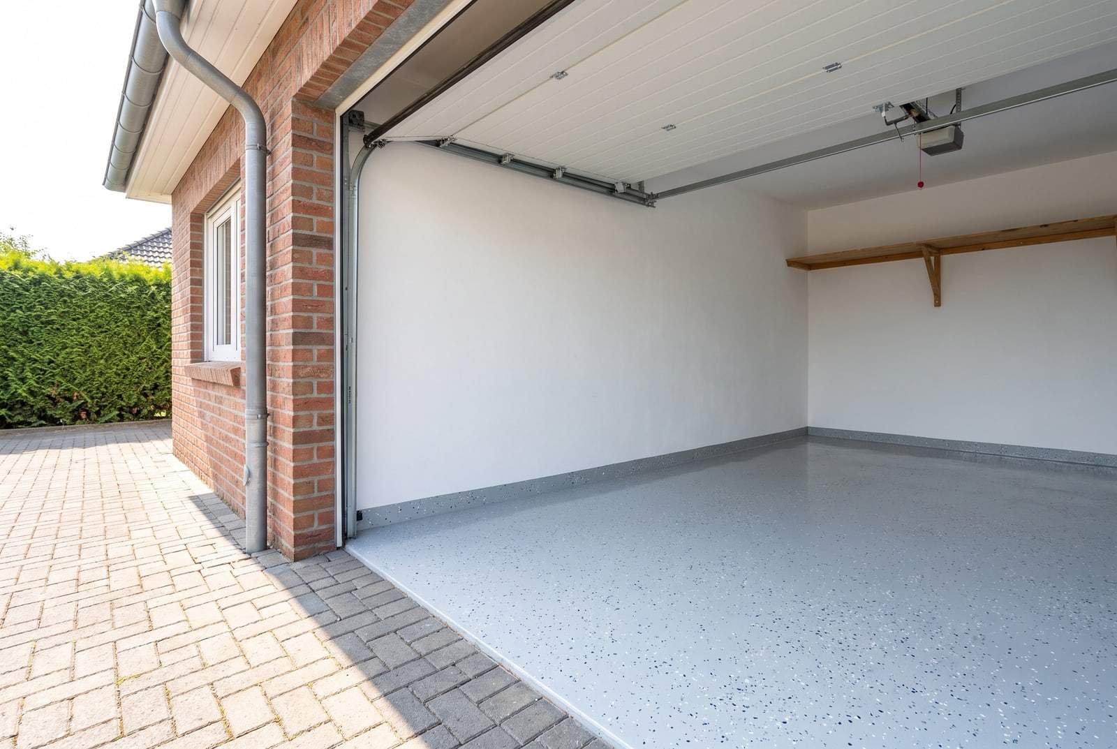 Offene Garage mit hellgrauer Bodenbeschichtung mit Farbchips und frisch gestrichenen Wänden