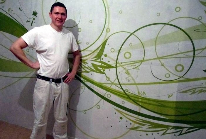 Viktor Horn vor einer gestalteten Wand mit grünem Rankenmotiv
